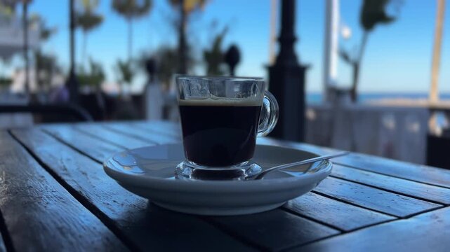 POV caf&eacute; en terraza con playa desenfocada en paseo mar&iacute;timo