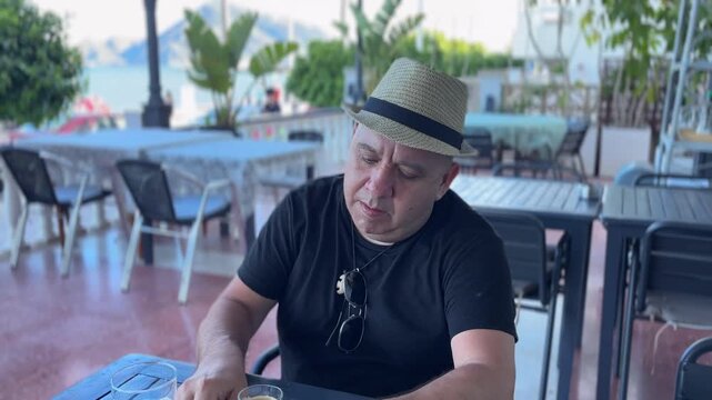 Hombre revolviendo caf&eacute; en terraza del paseo mar&iacute;timo