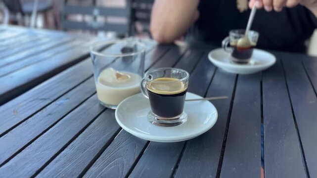 Primer plano caf&eacute; y licor con hombre removiendo al fondo