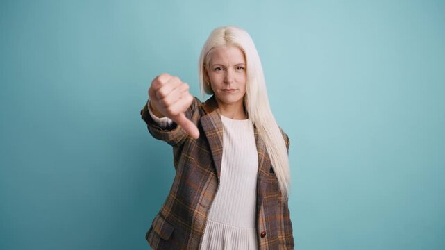 Displeased business woman showing a thumbs down gesture. Dissatisfied and critical person expressing a negative opinion and disagreement