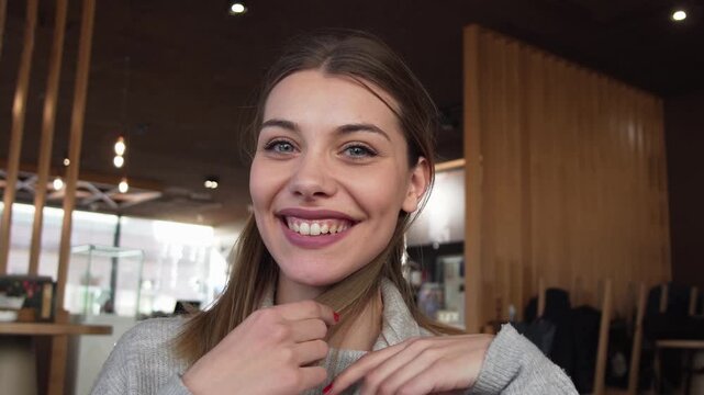 Young woman smiling in at camera  sitting in modern cafe with stylish wooden interior
