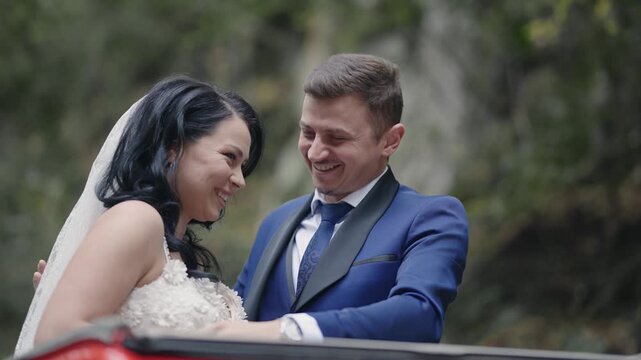 An emotional moment with joyful bride and groom exchange smiles during their wedding ceremony from convertible retro vintage car
