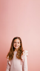 Fototapeta premium Cheerful young girl with long brown hair smiling confidently, standing on a solid pink background, showing joy