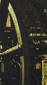 Water flows over a large wooden wheel in a mill by a river. The wheel turns as the water hits it. The scene shows the structure and the movement of the water.