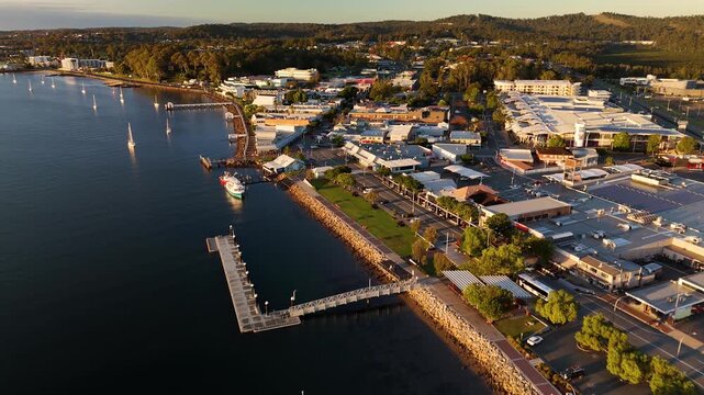 Aerial drone reverse view of Batemans Bay on the NSW South Coast, Australia, looking toward the CBD before revealing Clyde River Bridge on a sunny early morning in May 2026   