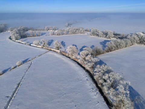 Wide winter landscape with snow-covered fields and frosty trees under a clear sky, Fuhse river, B&uuml;lten, Ilsede, Peine district, Lower Saxony, Germany