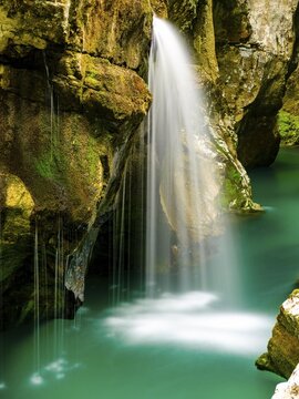 Waterfall plunges into the emerald green Soca River, Soca Valley, Triglav National Park, Bovec, Slovenia