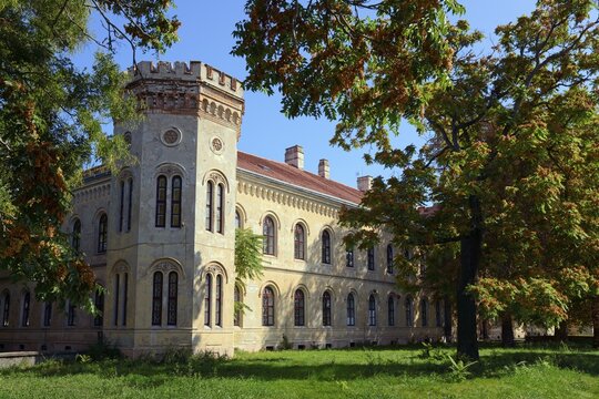 A historic Gothic-style castle surrounded by autumn trees under a clear blue sky, Officers' Palace, Komarno, Komarom, Komorn, Nitriansky kraj, Slovakia