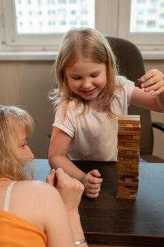 Little girl smiles while playing Jenga with another child