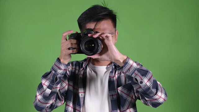 Photographer, man and camera on green screen for media production, digital content and creative advertising. Young male, photography and dslr with chroma key for video editing, hobby and studio work