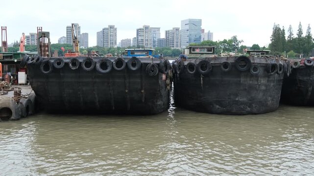 Industrial cargo barges and sand dredgers moored on the river in Ningbo China. Commercial freight vessels docked along a busy industrial city riverfront. Concept of maritime logistics 