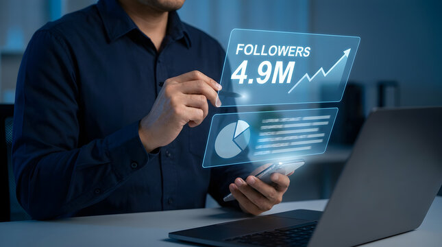Businessman using smartphone and laptop with social media followers growth analytics hologram showing 4.9M metric
