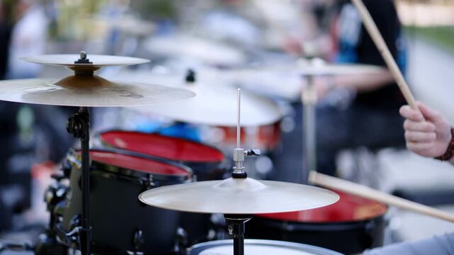 Drummer playing dynamic beat on drum kit with sticks, outdoor performance motion clip.
