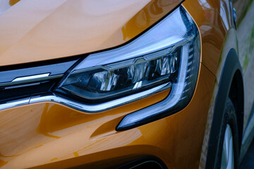 Dynamic front headlight design of a mustard orange contemporary car © Buğra Kaan Ersoy