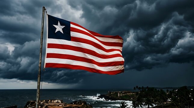 Liberian flag waving against a dramatic stormy sky over the atlantic ocean coastline