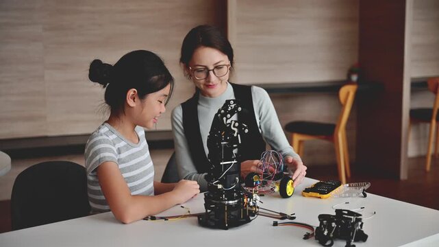 Helpful Female Teacher Guide Young Student To Assemble Robot In STEM Class