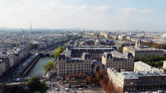 Aerial view of historical Paris cityscape featuring Seine river with Eiffel Tower on horizon in late afternoon light.