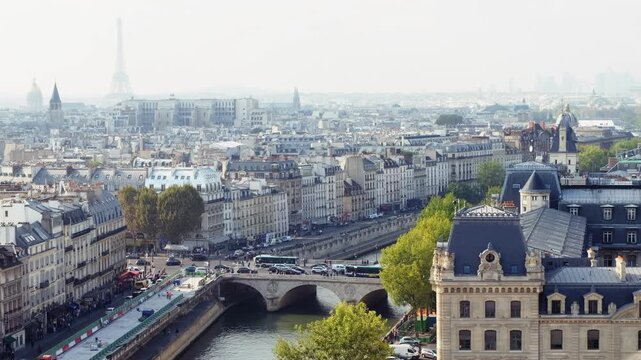 Panoramic aerial view of Paris cityscape with Eiffel Tower and Seine River bridges on a clear day.