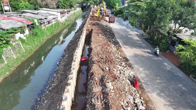 dredging mud on the riverbank in densely populated areas in the city center using heavy equipment such as excavators and dump trucks