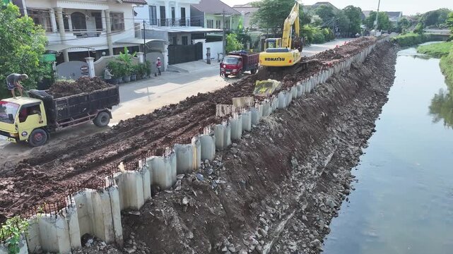 dredging mud on the riverbank in densely populated areas in the city center using heavy equipment such as excavators and dump trucks