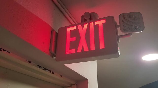 Indoor illuminated emergency exit sign attached above a doorway providing safety guidance and evacuation direction in a building environment.