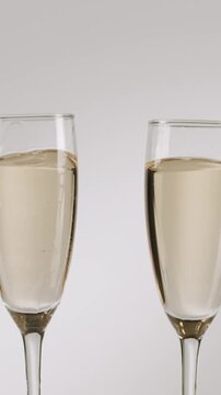 Slow motion detail shot of two glasses of champagne clinking together to celebrate, Beautiful slow-motion clip of two glasses of champagne clinking together isolated on a white background, vertical