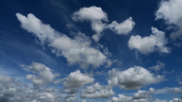 Timelapse of clouds white and grey appearing and disappearing against a blue sky.