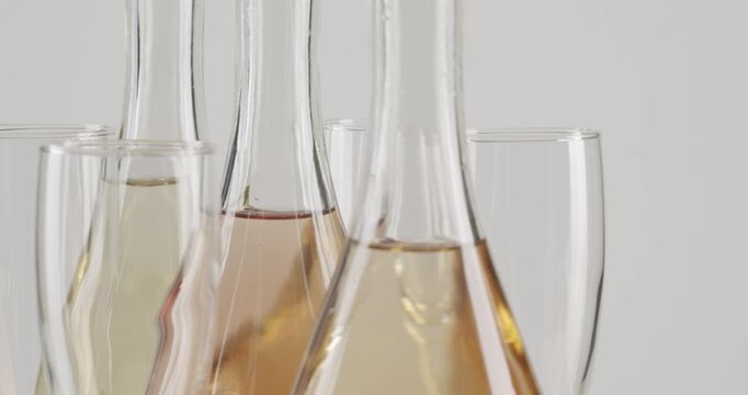 Elegant white and rose sparkling wine bottles slowly rotating against a clean, graduated grey background, showcasing their refined silhouette and the colors of the alcoholic beverage inside.