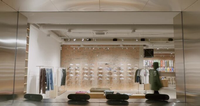 Modern Board Shop Interior With Trendy Clothes, Skateboards and Sneakers Displayed on Shelves. Stylish Retail Space with Brick Wall and Metal Fixtures. 