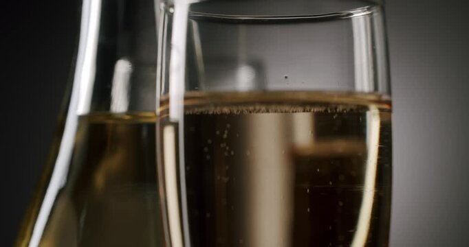 Sparkling wine bubbling in crystal glasses next to a bottle in a festive slow-motion shot, representing a celebration, anniversary, or special event on a dark elegant background.