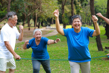 Obraz premium Happy Asian senior group running to finish line in park. Active elderly people enjoying outdoor exercise for healthy lifestyle and retirement wellness.