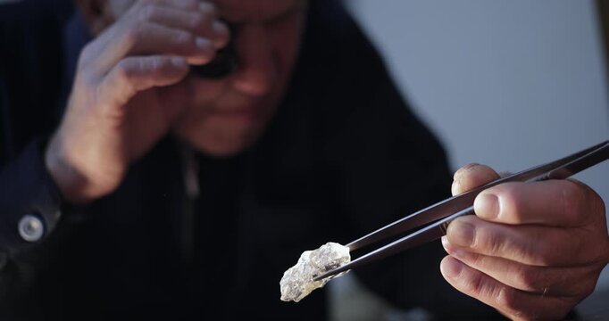 Jeweler inspecting rough diamond on workshop table with handheld lateral close up movement.