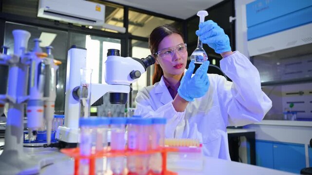 Female Scientist in Laboratory Using Glassware and Microscopy Equipment