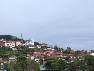 Fototapeta premium Hillside Town with Orange Tiled Roof Houses and Telecommunication Tower Under Cloudy Sky in Rural Laos