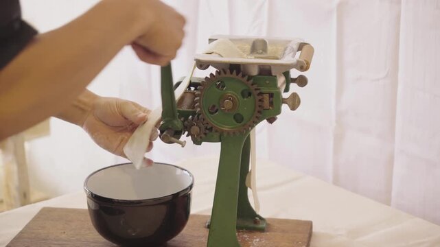 Video of a person making noodles with a manual mechanical machine