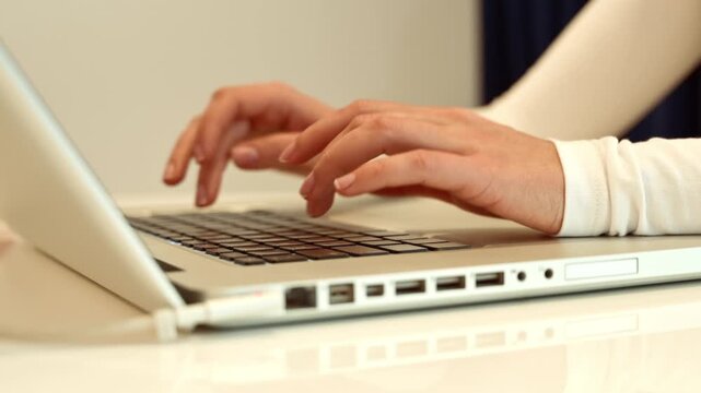 Woman's hands typing on laptop keyboard, engaging with technology, working efficiently with modern device, close-up motion clip.