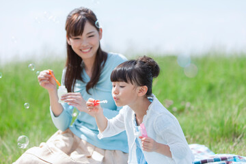 Obraz premium シャボン玉で遊ぶ母親と娘
