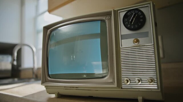 Slow cinematic camera pan across a retro kitchen featuring a small black and white television displaying no signal static interference. Nostalgic analog atmosphere evoking mid-century domestic life