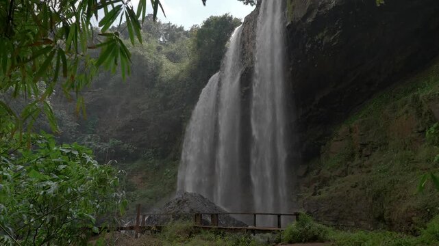 Static shot of Tad Kiet Ork waterfall in the jungle with a viewing platform in the foreground on the Bolaven Plateau, Laos.