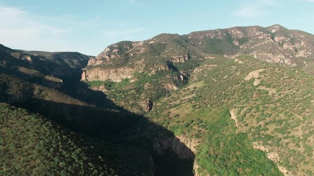 Aerial flyover of steep canyon walls, mountain ridges, and green vegetation in Sierra P&eacute;njamo