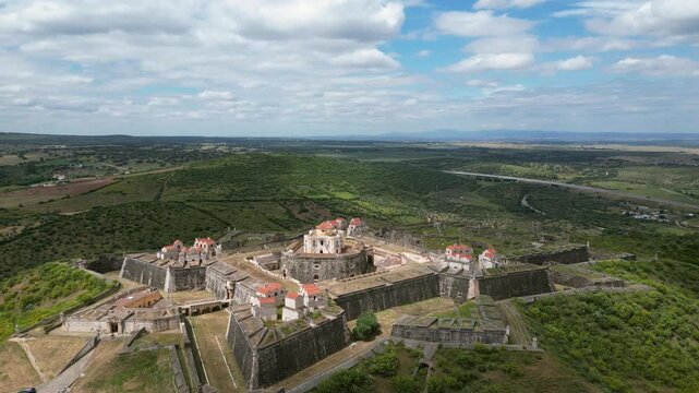 Aerial drone footage of Forte de Nossa Senhora da Gra&ccedil;a, Portugal: historic star-shaped fortress on a hill surrounded by vast Alentejo landscape. Ideal for travel and history projects.