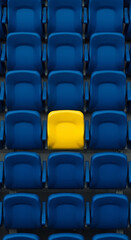 Naklejka premium A single yellow stadium seat standing out in a sea of blue seats symbolizing individuality and uniqueness in a crowded public venue.