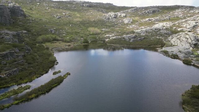 Aerial drone footage of Cov&atilde;o dos Conchos, Portugal: mountain lake with a unique circular spillway surrounded by Serra da Estrela landscape. Ideal for travel and nature projects.
