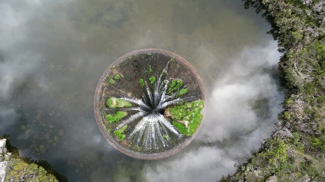Aerial drone footage of Cov&atilde;o dos Conchos, Portugal: mountain lake with a unique circular spillway surrounded by Serra da Estrela landscape. Ideal for travel and nature projects.