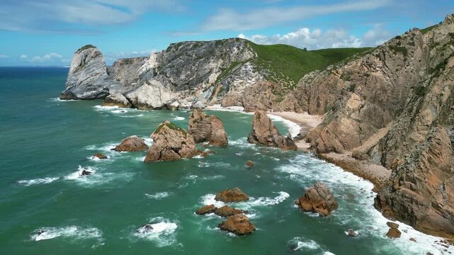 Aerial drone footage of Praia da Ursa, Portugal: dramatic sea stacks, Atlantic waves and rugged coastal scenery under natural light. Ideal for travel and nature projects.