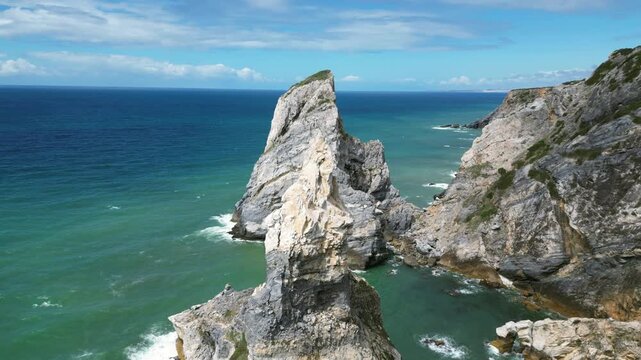 Aerial drone footage of Praia da Ursa, Portugal: dramatic sea stacks, Atlantic waves and rugged coastal scenery under natural light. Ideal for travel and nature projects.