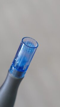 Dermapen device performing microneedling treatment. Aesthetic procedure for skin rejuvenation, stimulating collagen production.