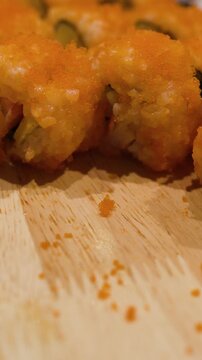 Close Up of Fresh Sushi Rolls with Orange Roe on Wooden Platter