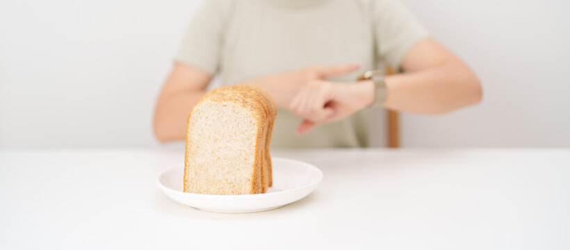 Happy smiling woman with whole wheat bread and time watch. concept of intermittent fasting, IF, meal timing, and choosing healthy carbohydrates for a balanced diet and weight loss management
