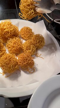 Serving Golden Crispy Fried Mee Krob Noodles with Metal Tongs